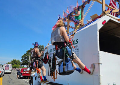 tree guys and gals repelling on truck in parade